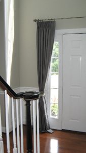 Silk pinch pleated drapes on decorative curtain rod in entryway.