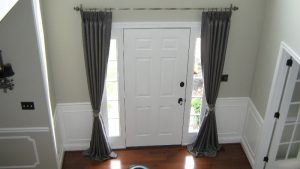 Pinch pleated silk drapes framing entryway.