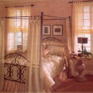 Quilted comforter and pillow shams with decorative throw pillows. Contrasting slightly puddle dust ruffle – sheer tab top drapery panels on the bed frame and the windows.