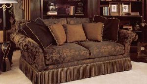 Large love seat with bullion fringe bottom border and accent pillows in contrasting fabrics and trims.