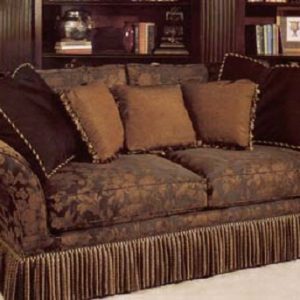 Large love seat with bullion fringe bottom border and accent pillows in contrasting fabrics and trims.