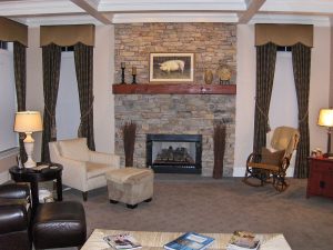 Fireplace between windows covered by Shaped cornice over draperies with tassle tie backs