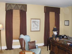 Shaped cornice, puddled draperies, upholstered chair