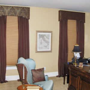 Shaped cornice, puddled draperies, upholstered chair