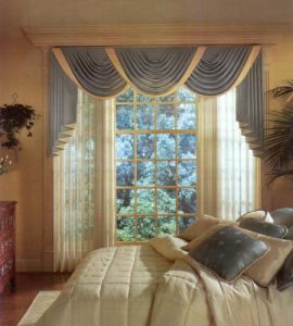 Classic swag and jabot valance with pinch pleated sheer drapes. Box pattern quilted comforter bedding ensemble.