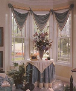 V-point valance in contrasting fabrics coordinating with table cover with welting and tassels.