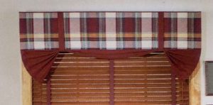 Strap up valance in plaid fabric over wood blind with decorative tape.