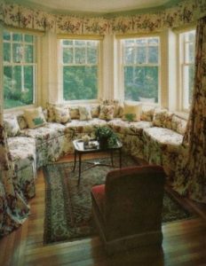Inverted box pleat valance over drapery panels coordinating with reupholstered sectional and pillows.